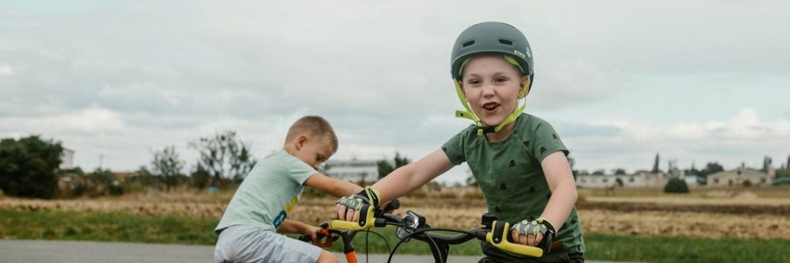 Two children riding bikes in a rural setting, showcasing active play.